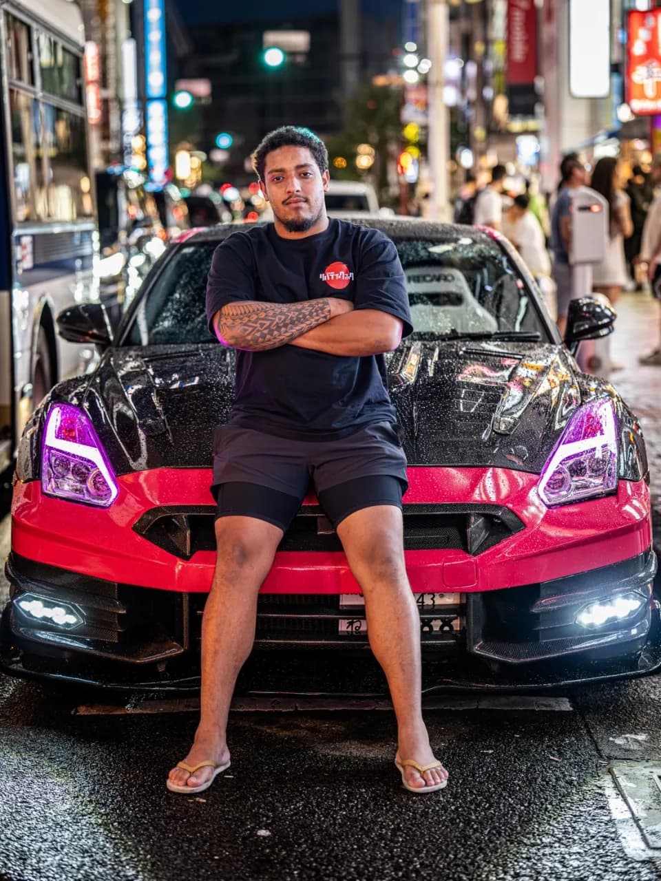 San - Your Driver & Guide sitting on the hood of the pink GT-R in Tokyo at night